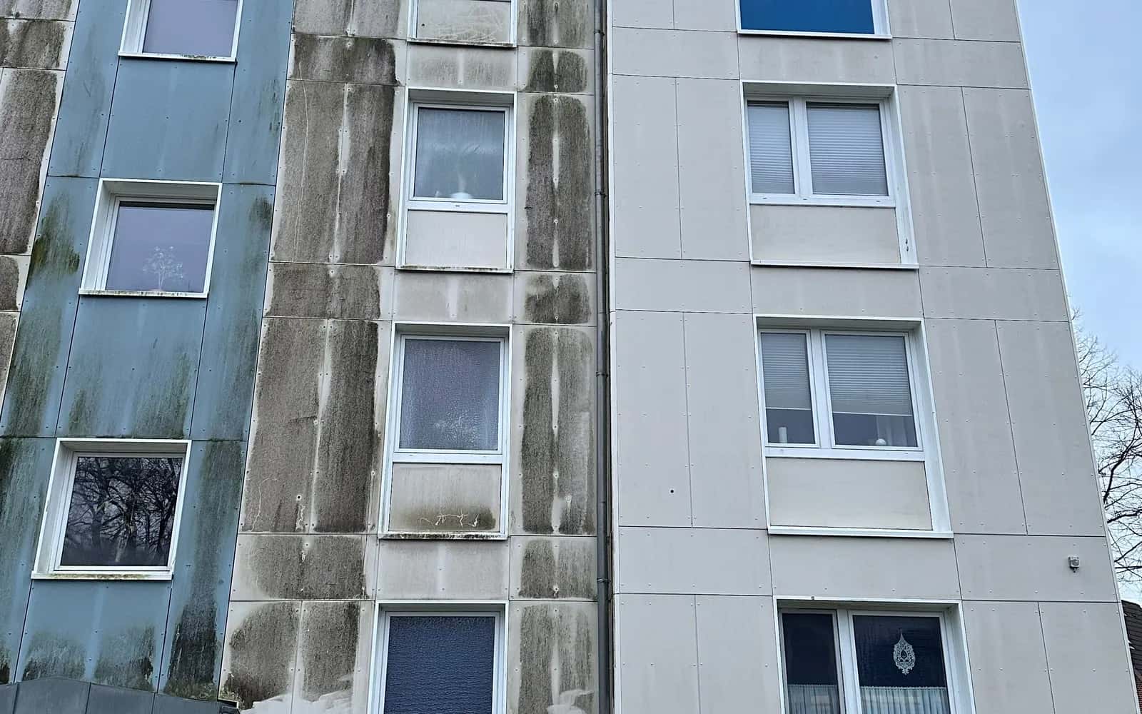 Mehrfamilienhaus im Bestand mit dunklen Ablaufspuren an der Fassade