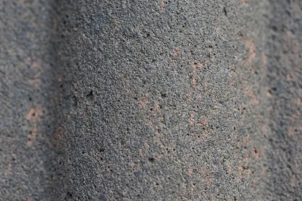 Körnige Sinterschicht eines grauen Betondachsteins in der Nahaufnahme