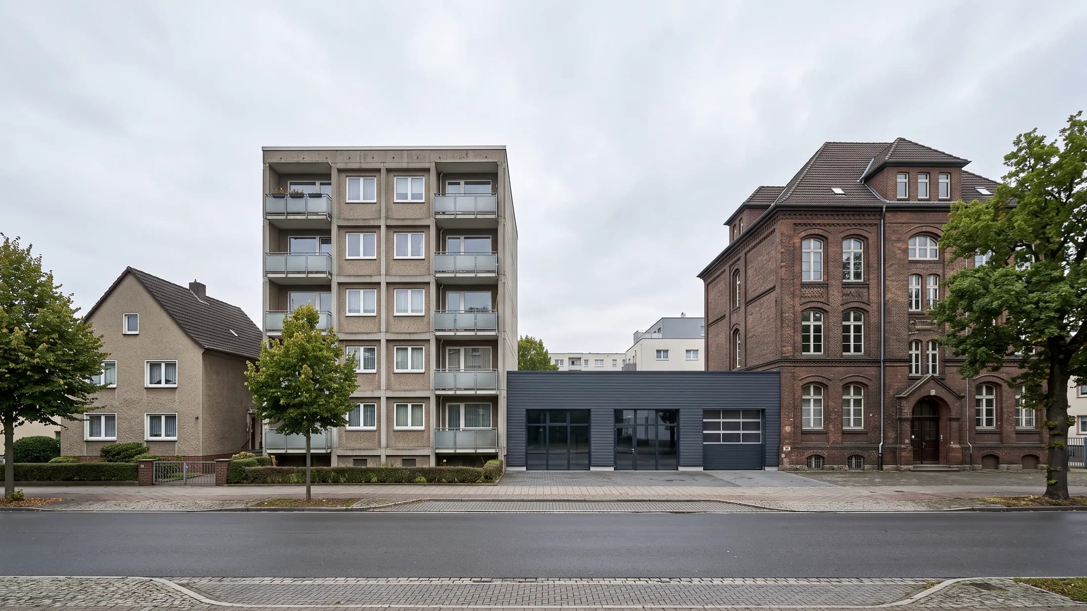 Straßenzug mit Wohnhaus, Mehrfamilienhaus, Gewerbehalle und öffentlichem Gebäude nebeneinander