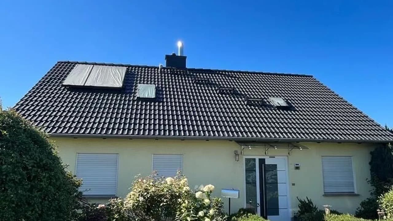 Wohnhaus mit Photovoltaikmodulen auf dem Dach, gereinigte Glasflächen im Sonnenlicht