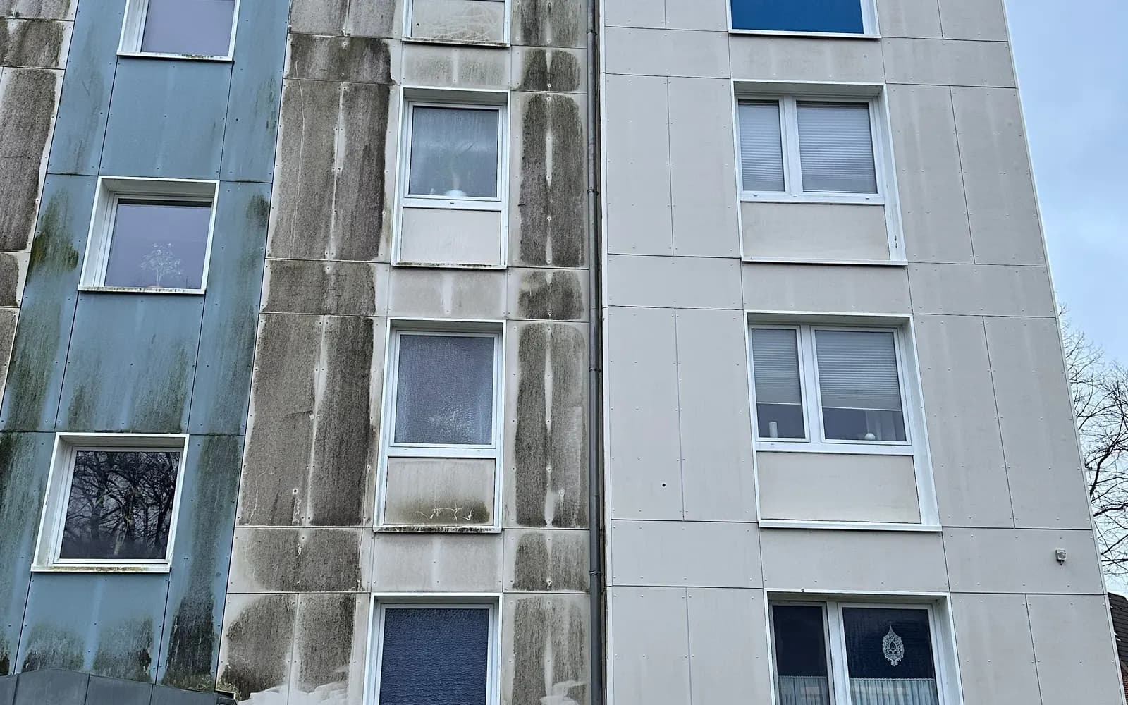 Mehrfamilienhaus im Bestand mit dunklen Ablaufspuren an der Fassade