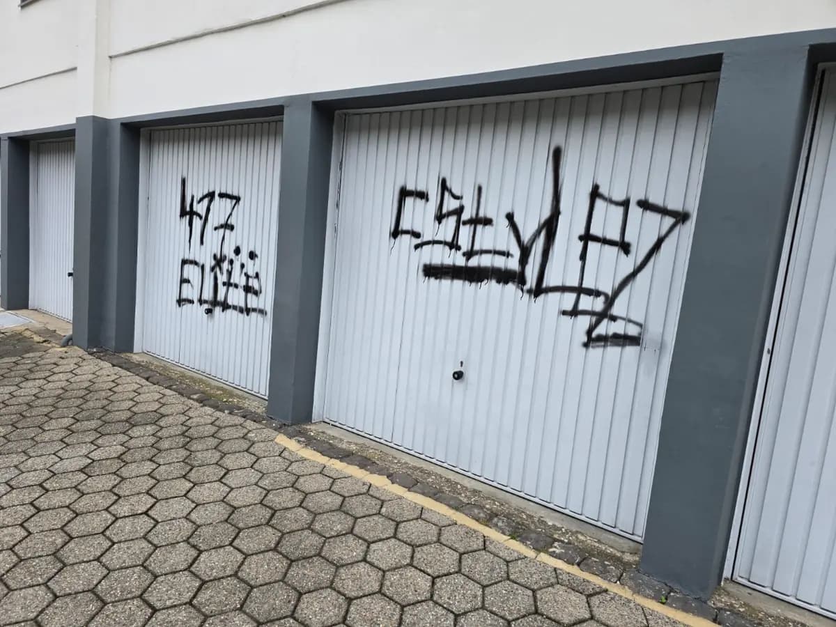 Zwei Garagentore einer Wohnanlage mit schwarzen Graffiti-Schriftzügen