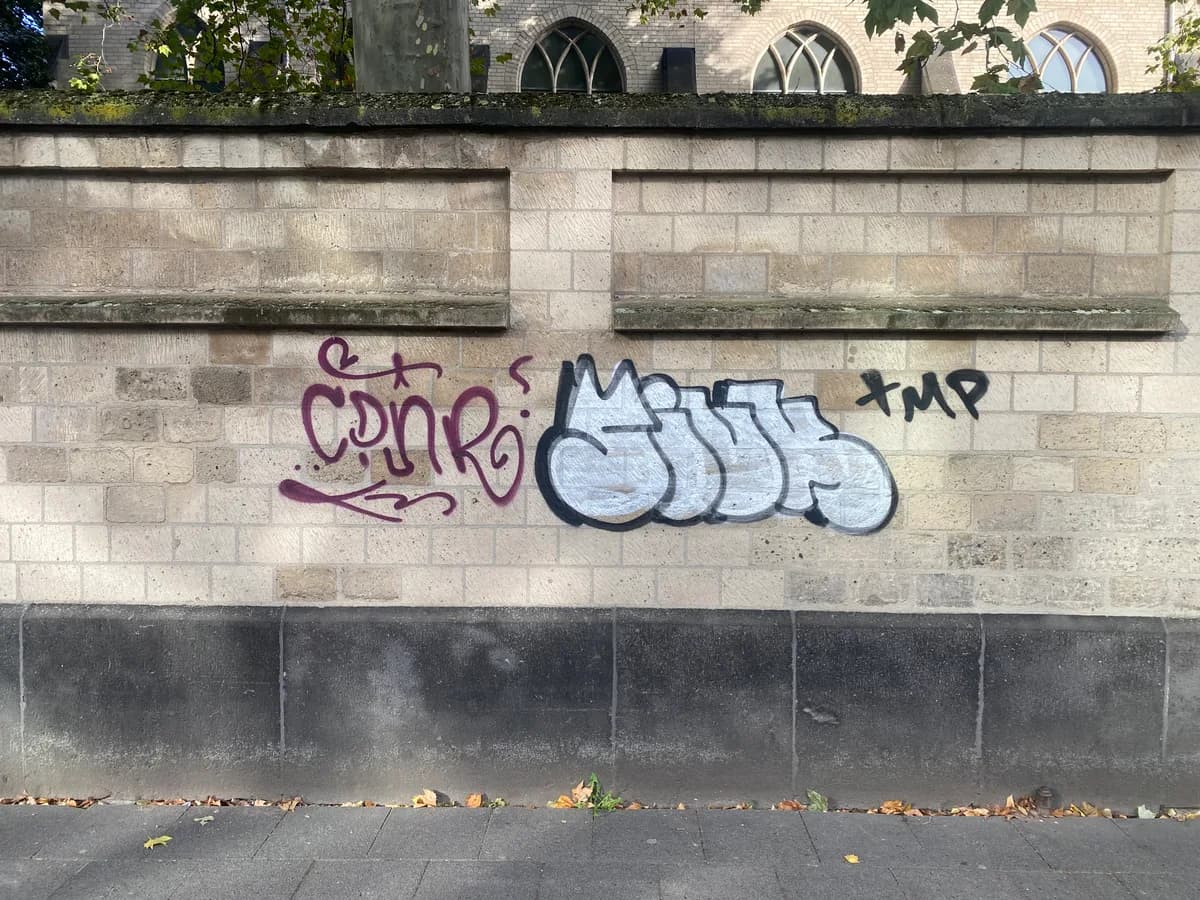 Natursteinmauer an einem Kirchengebäude mit großflächigem Graffiti-Schriftzug