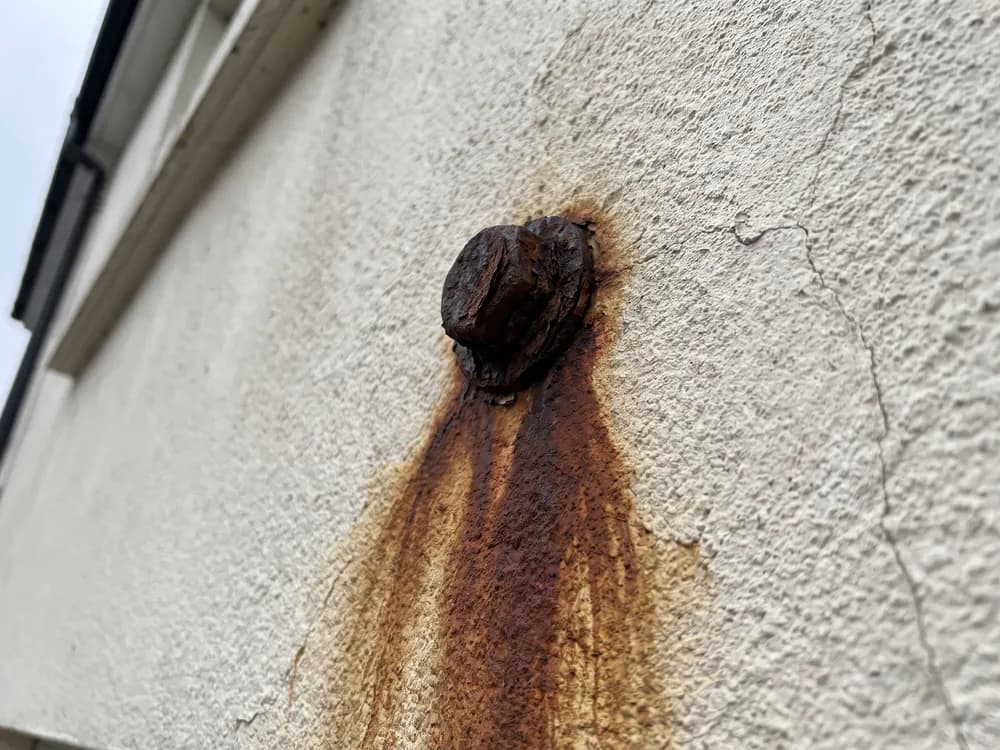 Braune Rostfahne, die aus einem Metallanker in den Putz eingelaufen ist