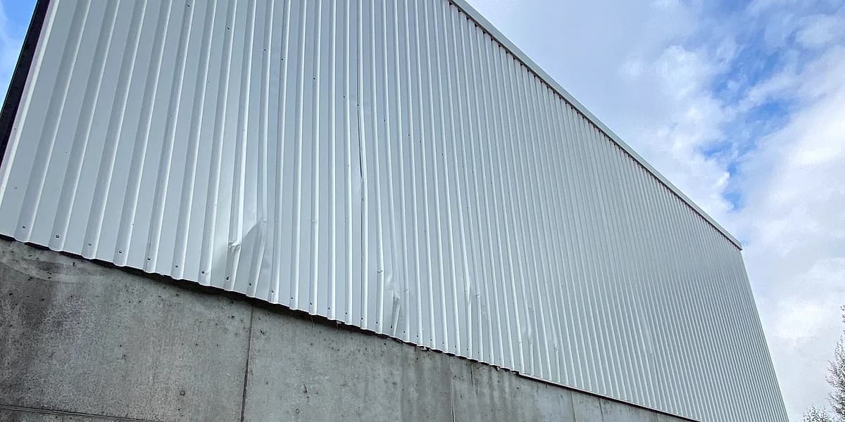 Gereinigte Hallenfassade aus hellem Trapezblech mit Betonsockel