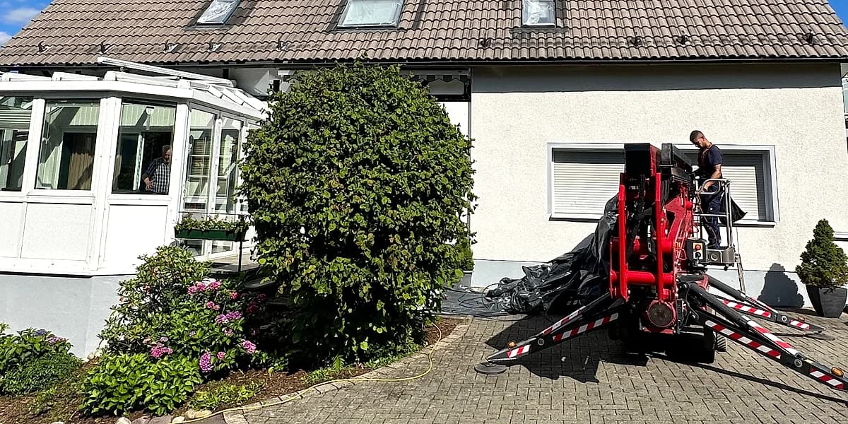 Mitarbeiter im Einsatz an einer Reihenhauszeile mit gelber Fassade