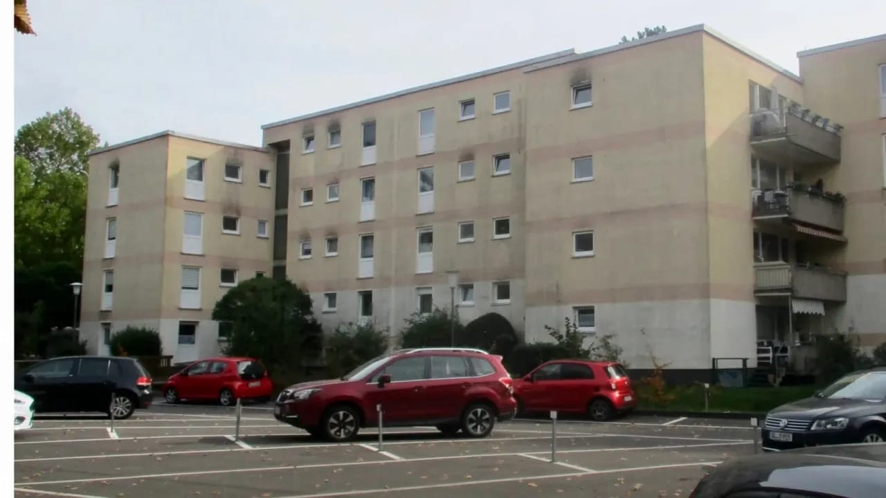 Mehrfamilienhaus am Parkplatz beim Übergang von grau verstreifter zu heller, sauberer Putzfassade