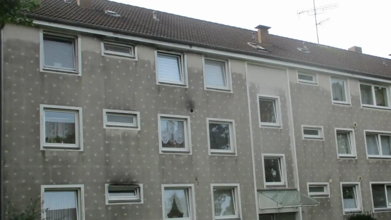 Mehrfamilienhaus mit grau-grünem Algenbelag auf der Putzfassade vor der Fassadenreinigung