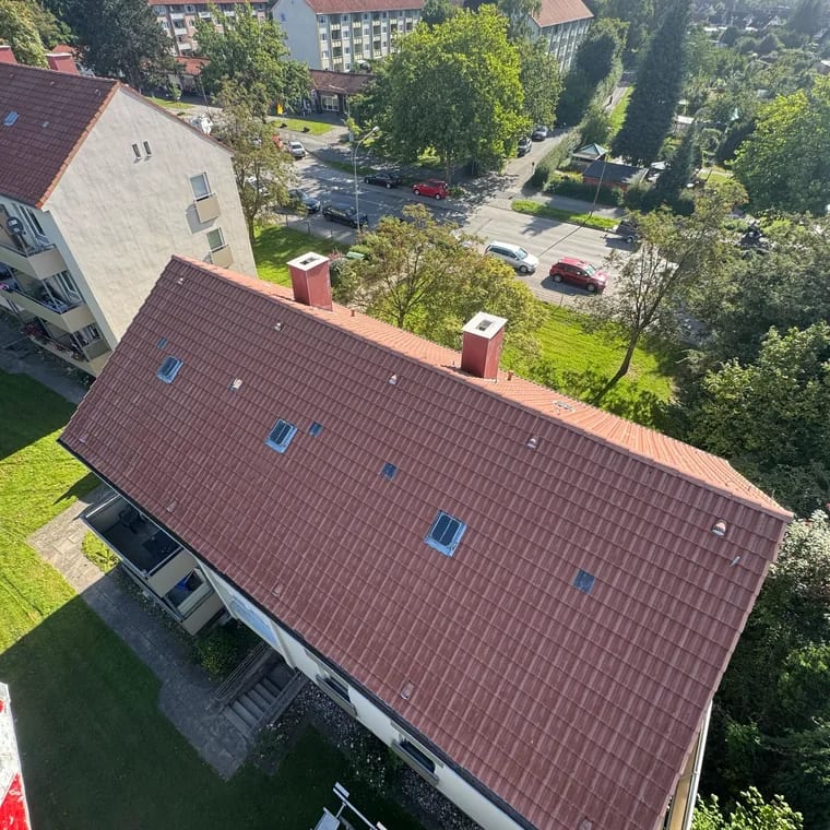 Dachfläche aus der Drohne beim Übergang von stumpf braun zu kräftig rot beschichtet