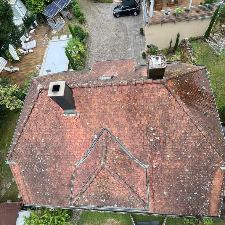 Ziegeldach aus der Drohne beim Übergang von vermoost zu gleichmäßig rot