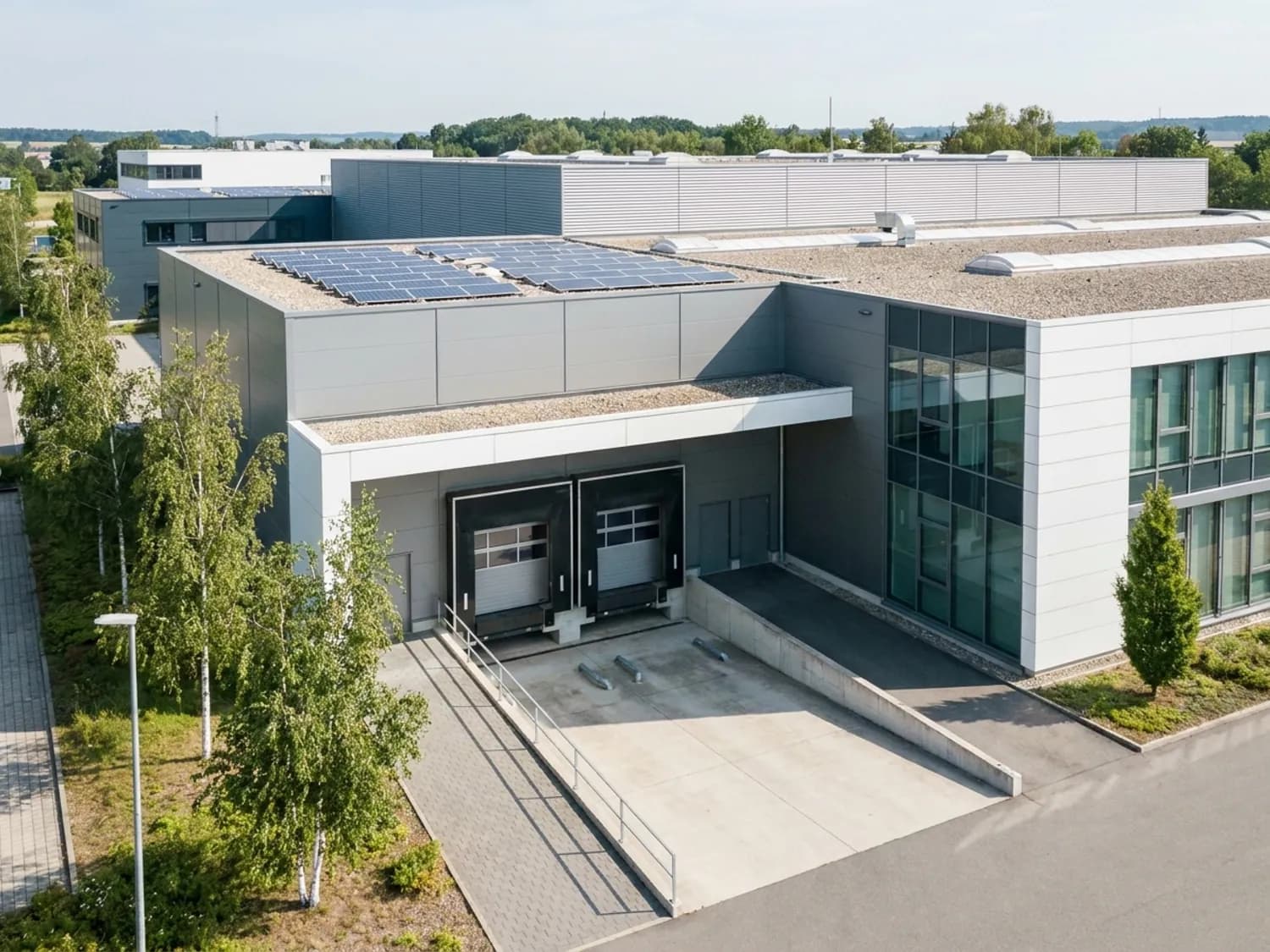 Modernes Gewerbe- und Logistikgebäude mit Ladezone und Photovoltaik-Dach
