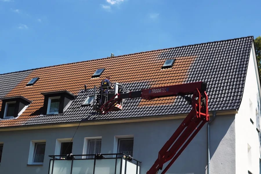 Arbeitsbühne im Einsatz an einem Wohnhaus, der Arbeitsbereich am Boden ist abgesichert
