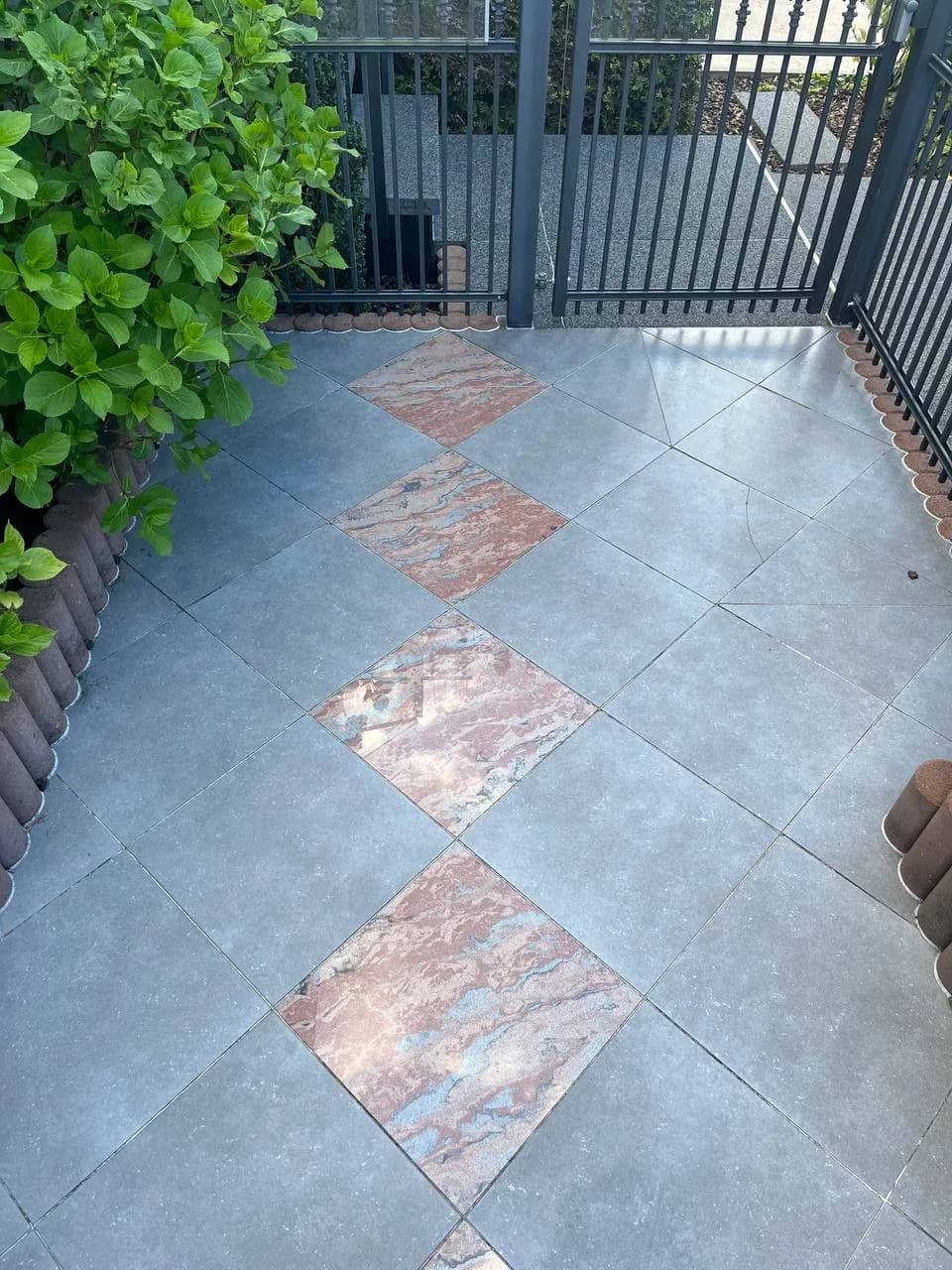 Dieselbe Terrasse nach der Reinigung, die roten Natursteinrauten zeichnen sich wieder klar ab