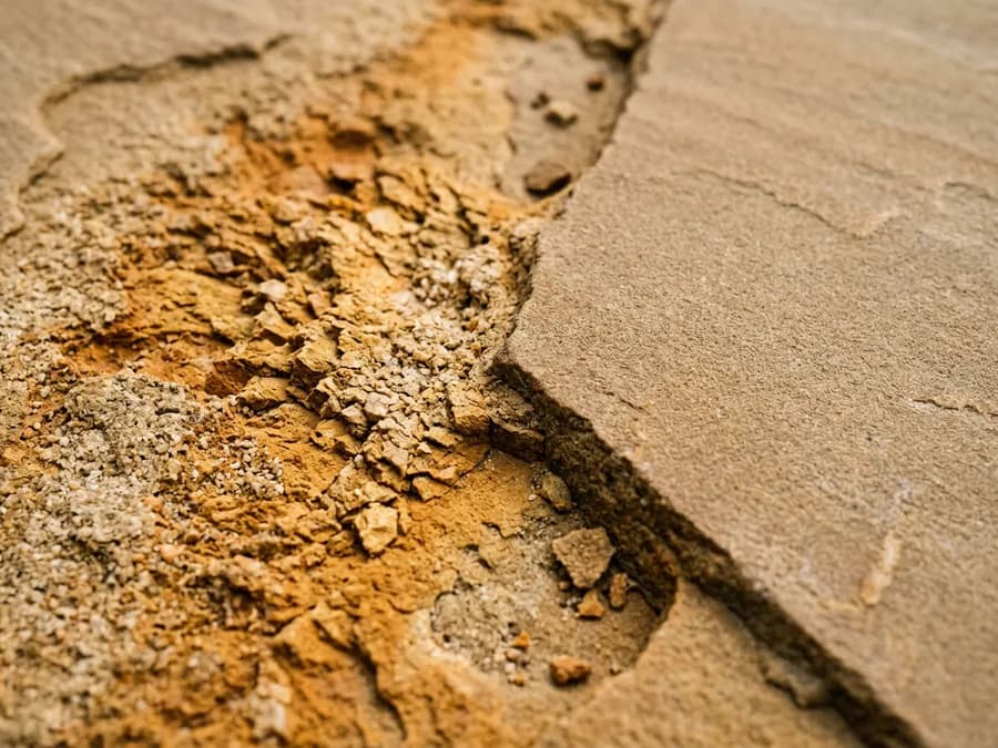 Sandsteinoberfläche, deren oberste Kornlage durch zu hohen Druck herausgesprengt wurde