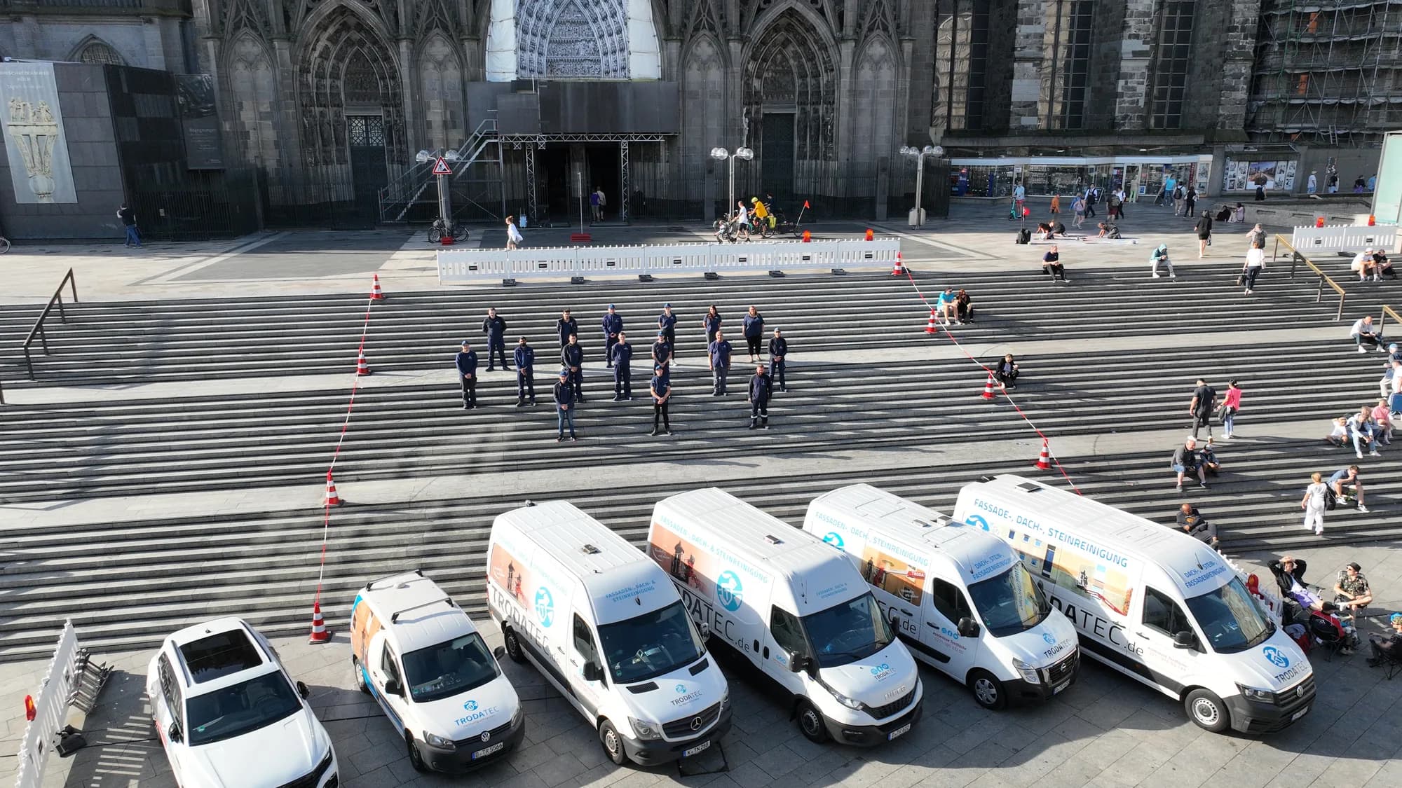 Sechs beschriftete TRODATEC-Einsatzfahrzeuge nebeneinander aufgereiht, dahinter das Team auf einer Freitreppe