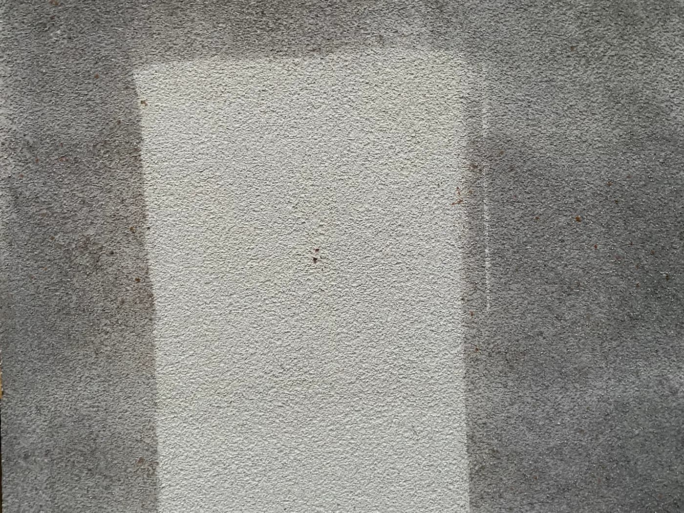 Deutlich sichtbare gereinigte Testfläche auf einer verschmutzten Putzfassade